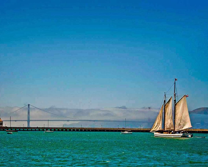 A sailing vessel on the San Francisco Bay with the Golden Gate Bridge in the background.